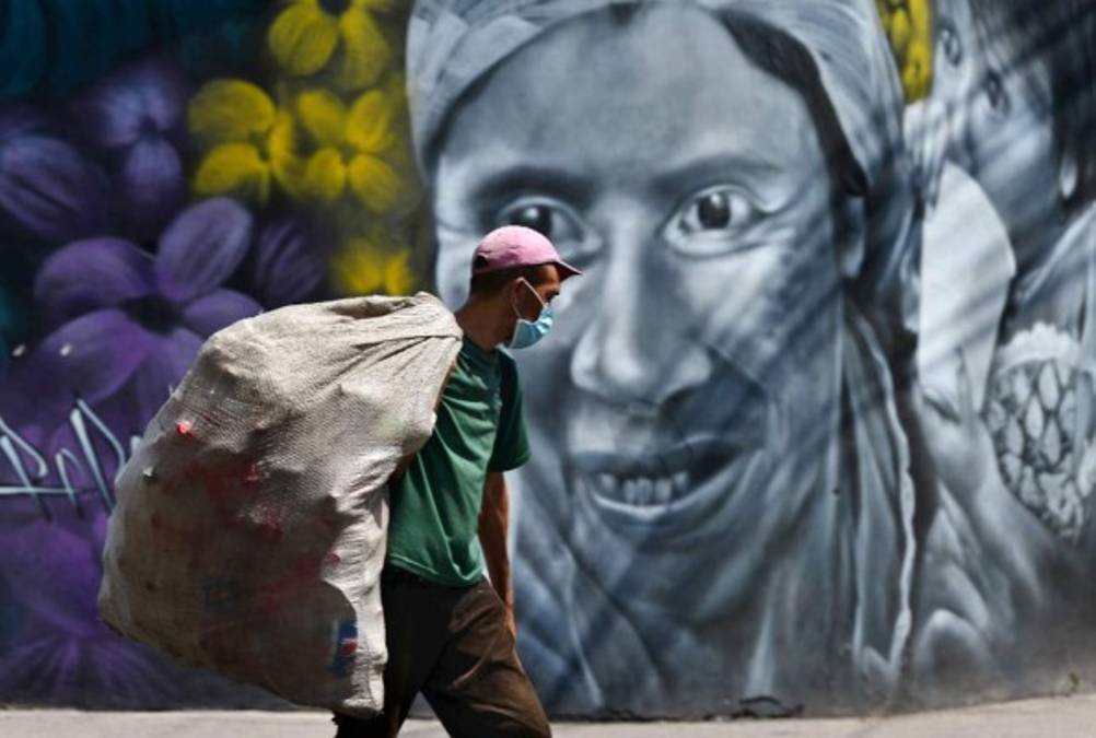 A man collects plastic bottles from the streets of Tegucigalpa on April 7, 2020 during the novel coronavirus, COVID-19, pandemic. - The coronavirus pandemic has killed more than 75,000 people worldwide since it emerged in China in December, according to a tally compiled by AFP from official sources at 0945 GMT on Tuesday. (Photo by Orlando SIERRA / AFP)
