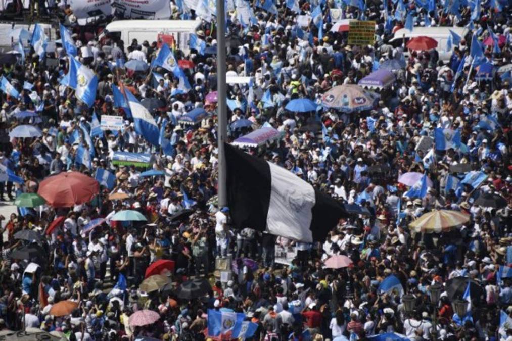 Miles de guatemaltecos se reunieron en la Plaza de la Constitución donde ondearon una bandera donde el azul fue sustituido por dos franjas negras en rechazo a los escándalos de corrupción. / AFP PHOTO / Johan ORDONEZ