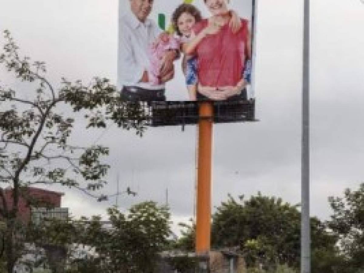 An election campaign banner depicting Costa Rican presidency candidate Antonio Alvarez Desanti of the National Liberation Party (PLN) with his wife Nuria Marin and their grandchildren, is seen on January 4, 2018 in San Jose ahead of the upcoming February 4 presidential elections. Costa Ricans will go to the polls on February 4 to elect their next president, in a climate of uncertainty in which nearly half of the population remains undecided and the candidate with further support in the polls is far from the minimum 40% needed to win in the first round. / AFP PHOTO / Ezequiel BECERRA