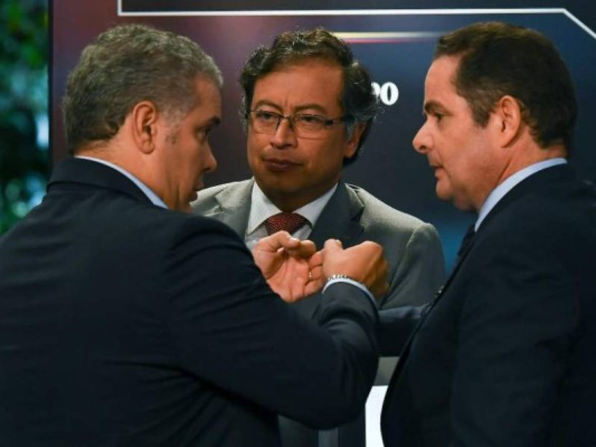 (L-R): Colombian presidential candidates Ivan Duque for the Democratic Center Party; Gustavo Petro for the Colombia Humana Party; and German Vargas Lleras for the Cambio Radical Party confer on stage during a TV debate in Bogota on May 24, 2018. Colombia will hold presidential elections on May 27th. / AFP PHOTO / Luis ACOSTA