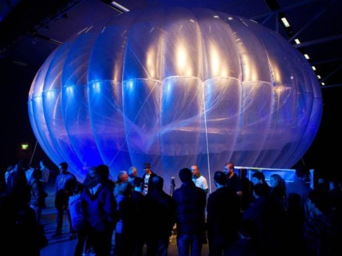 Los visitantes se paran junto a un centro de Internet WiFi de gran altitud, un globo de Google Project Loon, que se exhibe en el Museo de la Fuerza Aérea en Christchurch el 16 de junio de 2013. Google reveló planes ultrasecretos el 15 de junio para enviar globos al borde del espacio con el noble objetivo de llevar Internet a las dos terceras partes de la población mundial que actualmente no tiene acceso a la web. FOTO AFP / MARTY MELVILLE (Foto de Marty Melville / AFP)