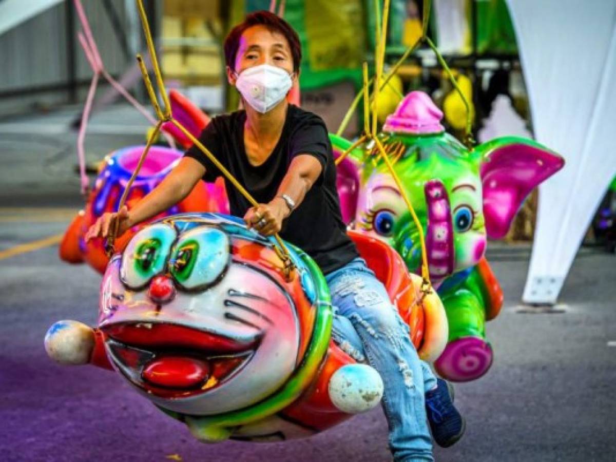 A man with a facemask rides a carousel in Bangkok on February 1, 2020. - The World Health Organisation declared a global emergency over the new coronavirus, as China reported on January 31 the death toll had climbed to 259 with nearly 10,000 infections. (Photo by Mladen ANTONOV / AFP)