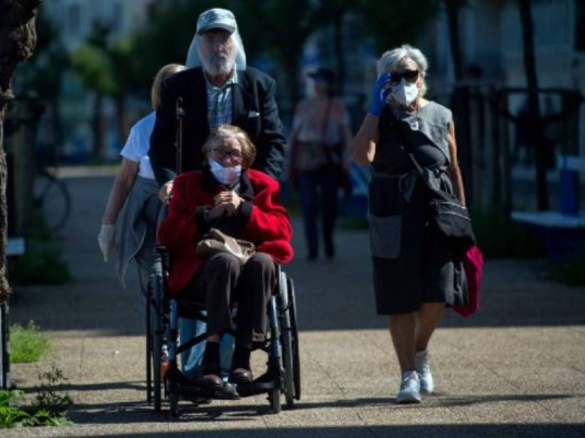 A man wearing a face shield pushes an elderly woman on a wheelchair along a esplanade in La Concha beach in San Sebastian, on May 2, 2020, during the hours allowed by the government to exercise, for the first time since the beginning of a national lockdown to prevent the spread of the COVID-19 disease. - All Spaniards are again allowed to leave their homes since today to walk or play sports after 48 days of very strict confinement to curb the coronavirus pandemic. After allowing children under 14 to go out since April 26, the government has again eased the conditions of the confinement imposed on March 14, which was one of the strictest in the world. (Photo by ANDER GILLENEA / AFP)