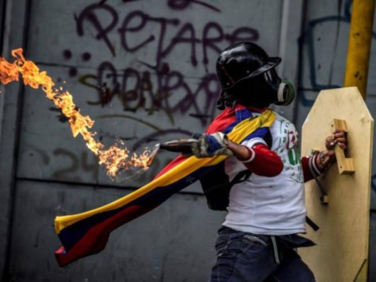 An opposition activist clashes with the police during a march towards the Supreme Court of Justice (TSJ) in an offensive against President Maduro and his call for Constituent Assembly in Caracas on July 22, 2017.The Legislative power, controlled by the opposition, appointed Friday a parallel supreme court in a public session claiming the TSJ judges had been illegally appointed by the parliaments former pro-government majority. / AFP PHOTO / JUAN BARRETO