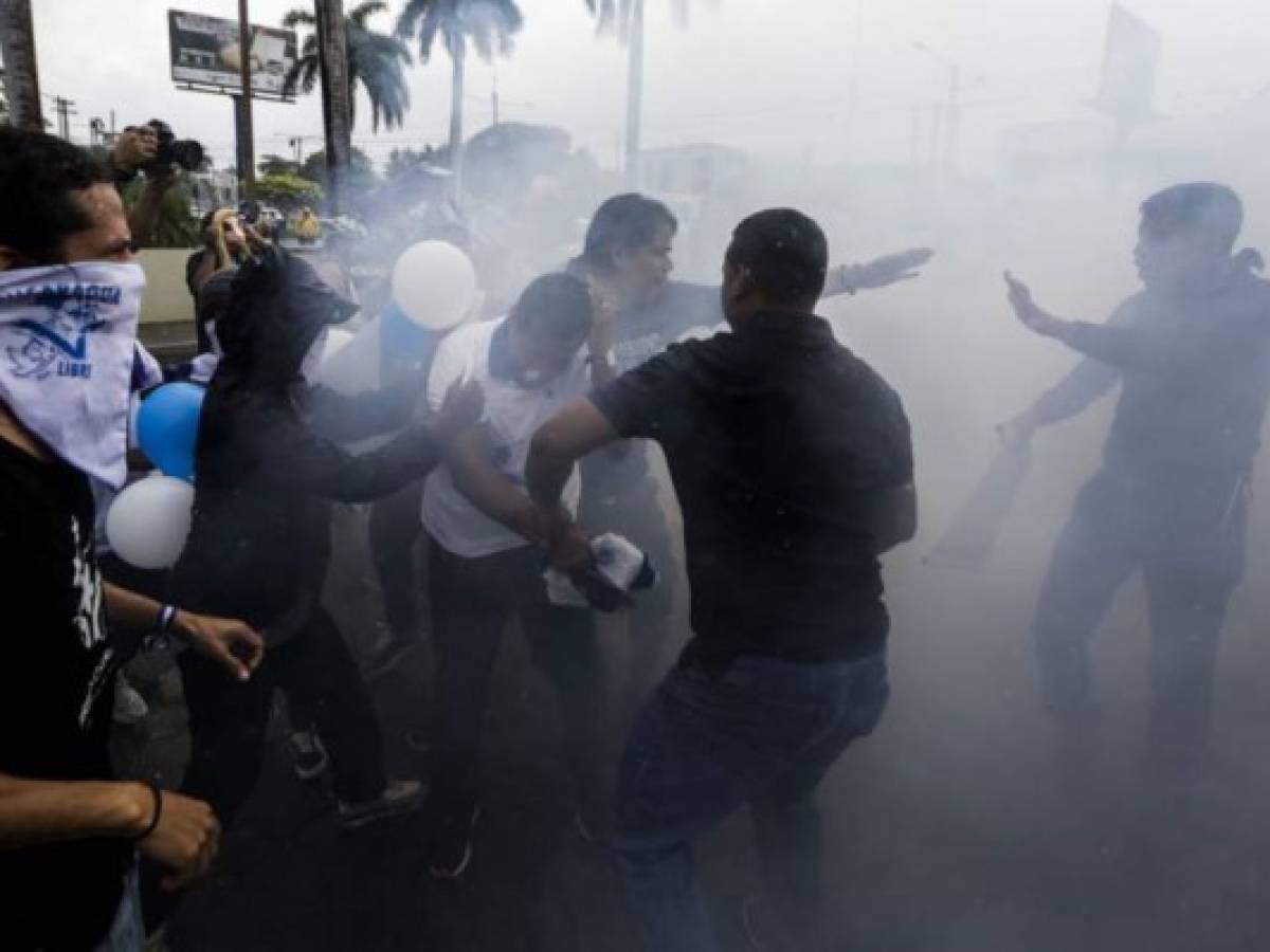 Protesters react after riot police threw sound grenades during a demonstration to demand the release of political prisoners, the cessation of violence in the north of the country and in honour 16-year-old student Matt Romero, who was shot dead a year ago during clashes between anti-government protesters and riot police and paramilitaries, in Managua on September 21, 2019. - The Central American country plunged into crisis in April 2018 after widespread opposition protests broke out, and a brutal crackdown over the next four months by President Daniel Ortega's troops left 325 people dead, 800 in prison and thousands in exile. (Photo by Inti OCON / AFP)