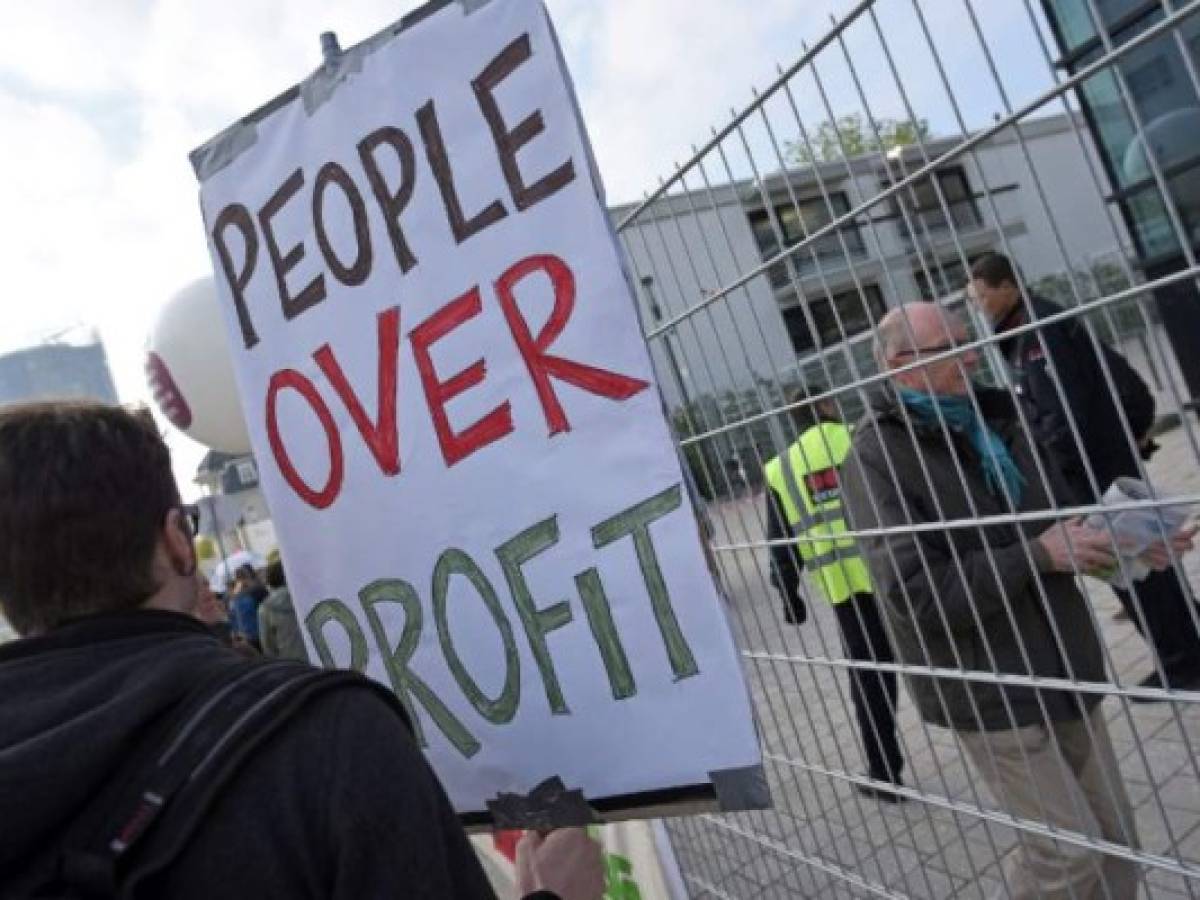 (FILES) In this file photo taken on April 28, 2017 a protester holds a banner during a demonstration on the sidelines of the general assembly of German pharmaceutical group Bayer and the planned merger between Bayer and US seed and pesticide maker Monsanto, in Bonn. - Germany chemicals and pharmaceuticals giant Bayer said on November 29, 2018, it would slash 12,000 jobs in a major restructuring following the takeover of Monsanto, enabling the group to save 2.6 billion euros a year from 2022. (Photo by Henning Kaiser / dpa / AFP) / Germany OUT