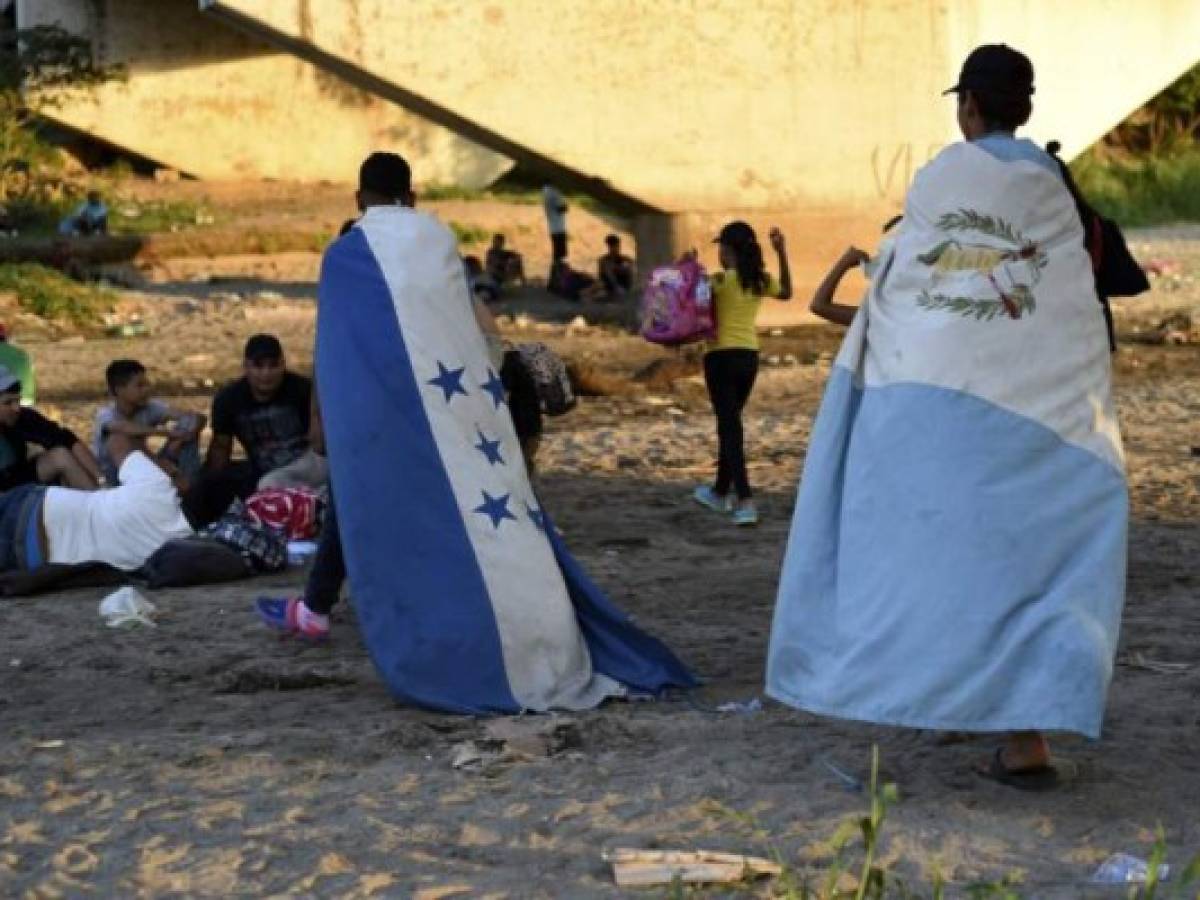 Migrants wearing a Honduran (L) and a Guatemalan flag wait to cross from Tecun Uman, Guatemala, to Ciudad Hidalgo, Mexico, on January 18, 2020. - On the eve, Mexican President Andres Manuel Lopez Obrador offered 4,000 jobs to members of the caravan in an attempt to dissuade them from traveling on to the United States. The caravan, which formed in Honduras this week, currently has around 3,000 migrants, Lopez Obrador said. (Photo by Johan ORDONEZ / AFP) Migrants wearing a Honduran (L) and a Guatemalan flag wait to cross from Tecun Uman, Guatemala, to Ciudad Hidalgo, Mexico, on January 18, 2020. - On the eve, Mexican President Andres Manuel Lopez Obrador offered 4,000 jobs to members of the caravan in an attempt to dissuade them from traveling on to the United States. The caravan, which formed in Honduras this week, currently has around 3,000 migrants, Lopez Obrador said. (Photo by Johan ORDONEZ / AFP)
