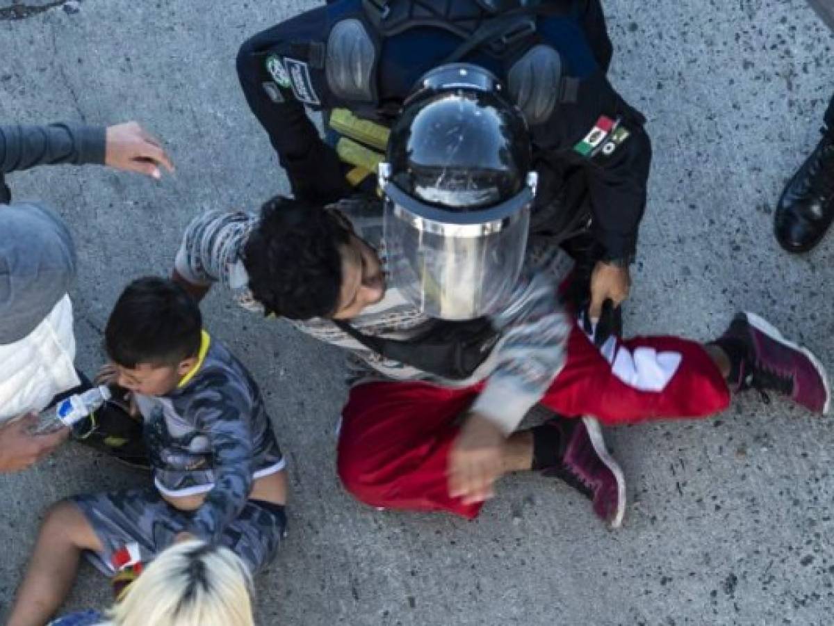 Central American migrants are stopped by Mexican police forces as they reach the El Chaparral border crossing, in Tijuana, Baja California State, Mexico, on November 25, 2018. - Hundreds of migrants attempted to storm a border fence separating Mexico from the US on Sunday amid mounting fears they will be kept in Mexico while their applications for a asylum are processed. An AFP photographer said the migrants broke away from a peaceful march at a border bridge and tried to climb over a metal border barrier in the attempt to enter the United States. (Photo by Pedro PARDO / AFP)