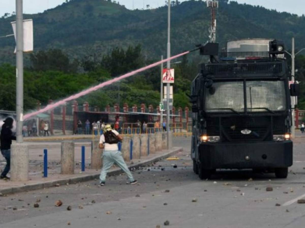 Security forces use a water cannon to disperse demonstrators during a university students' protest against the reelection of President Juan Orlando Hernandez in Tegucigalpa on October 18, 2017.39 days ahead of national elections students gathered under the University Student Movement (MEU) assure presidential reelection is not allowed in the country. / AFP PHOTO / ORLANDO SIERRA