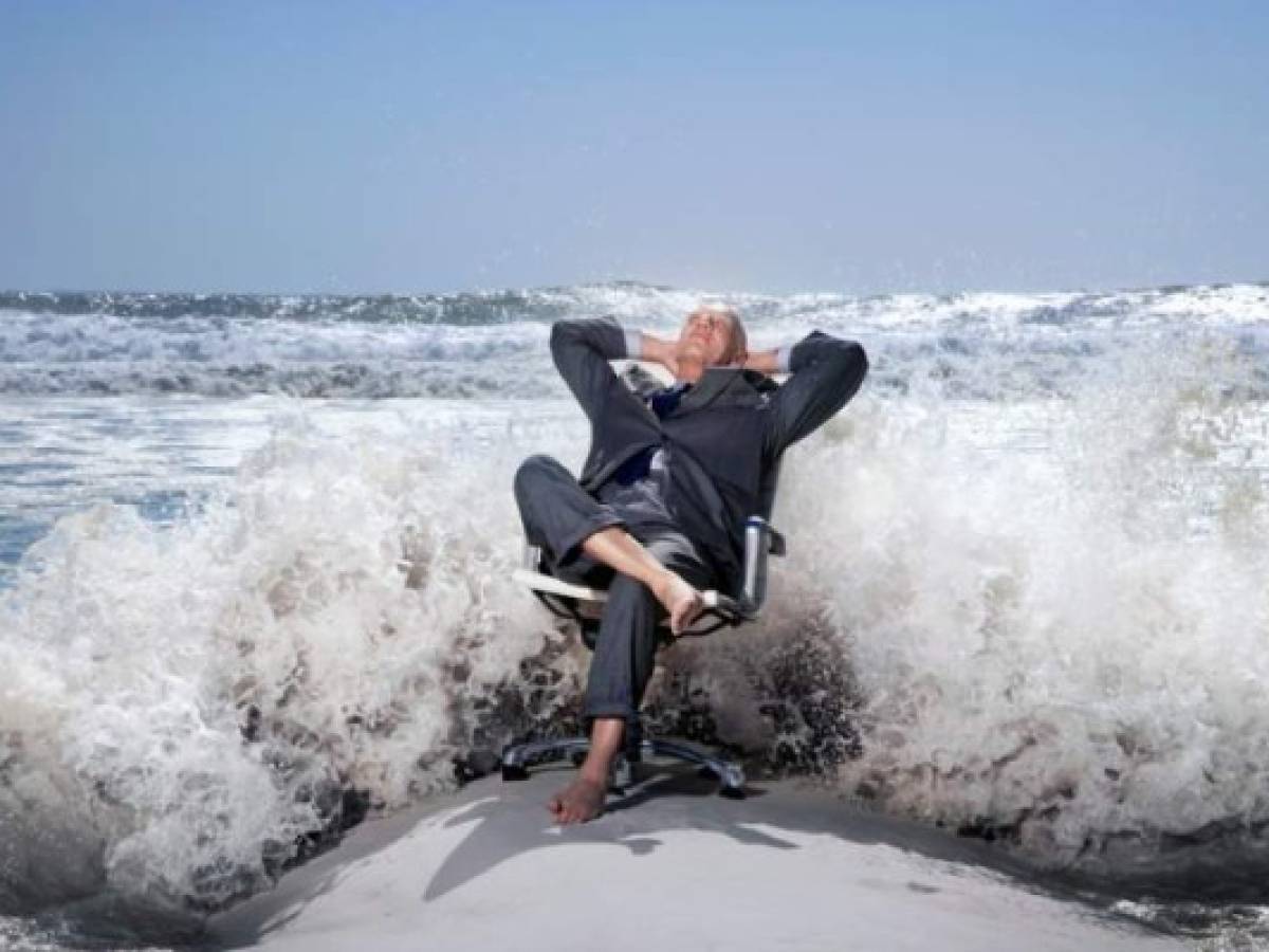 Senior business man sitting on office chair on beach, being splashed by waves Senior business man sitting on office chair on beach, being splashed by waves