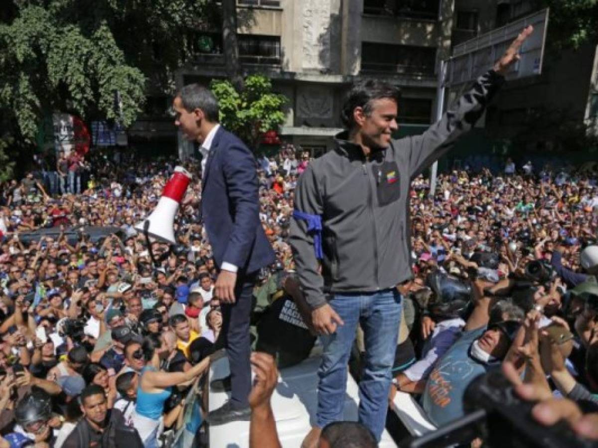 Venezuelan opposition leader and self-proclaimed acting president Juan Guaido (L) and high-profile opposition politician Leopoldo Lopez, who had been put under home arrest by Venezuelan President Nicolas Maduro's regime, greet supporters after being joined by members of the Bolivarian National Guard to oust Maduro, in Caracas on April 30, 2019. - Guaido -- accused by the government of attempting a coup Tuesday -- said there was 'no turning back' in his attempt to oust President Nicolas Maduro from power. (Photo by Cristian HERNANDEZ / AFP)