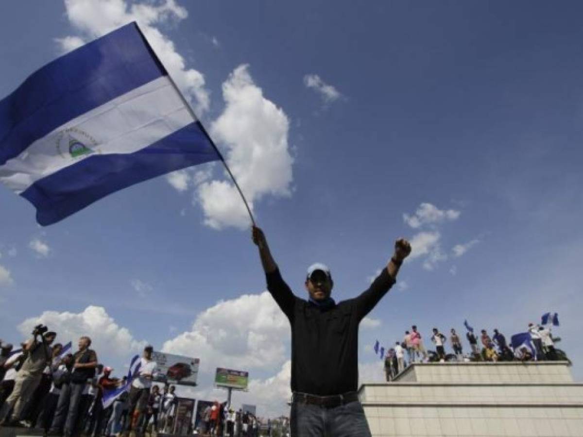 A demonstrator waves a Nicaraguan national flag during the 'Walk for Peace and Dialogue' where many demand Nicaraguan President Daniel Ortega and his wife Vice-President Rosario Murillo to step down, in Managua on April 23, 2018.Ortega was under pressure from widespread street unrest on Monday despite backing down on a contentious pension reform plan that triggered days of violence in which at least 27 people have been killed. / AFP PHOTO / Inti OCON