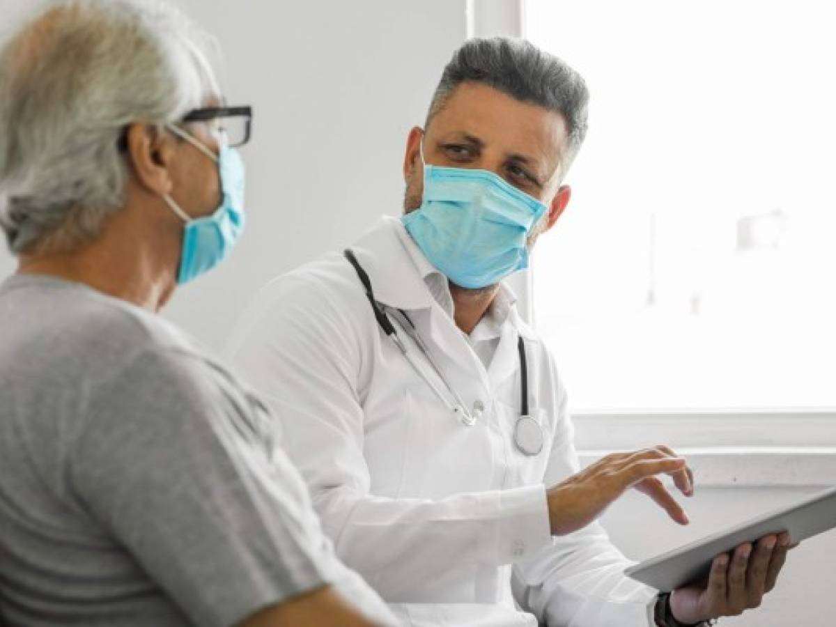 Doctor using digital tablet and talking to patient at home