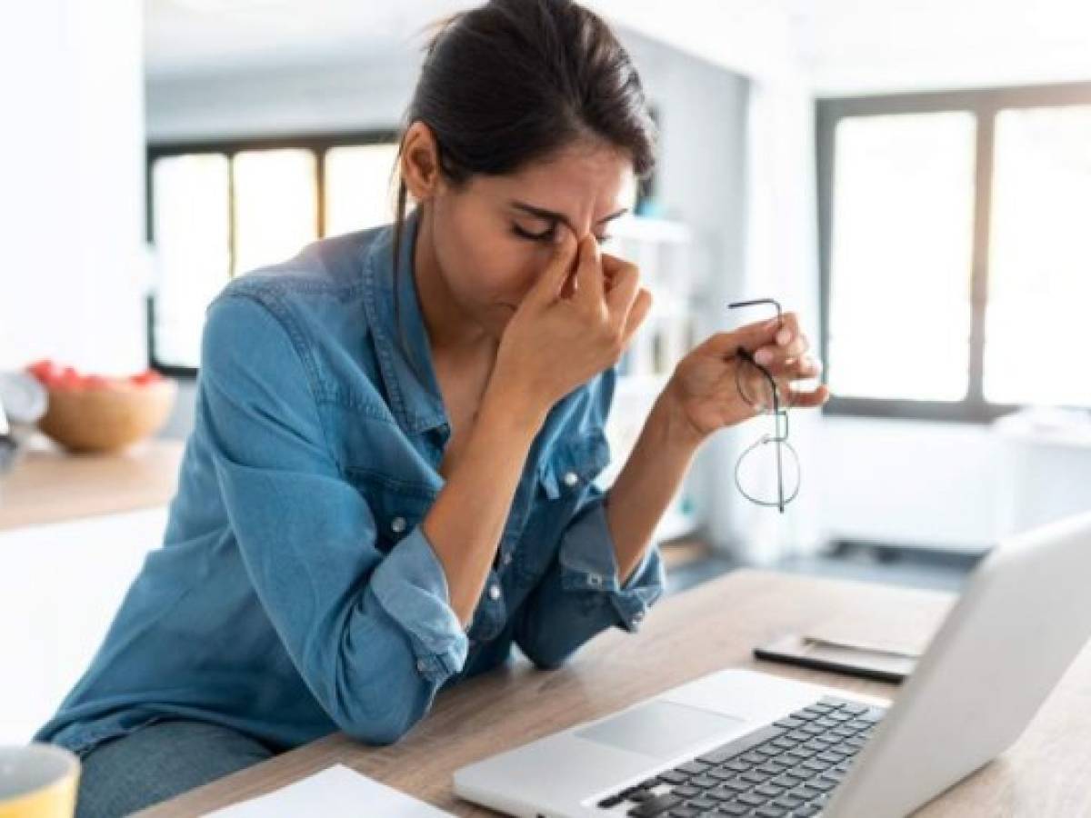 Shot of stressed business woman working from home on laptop looking worried, tired and overwhelmed.