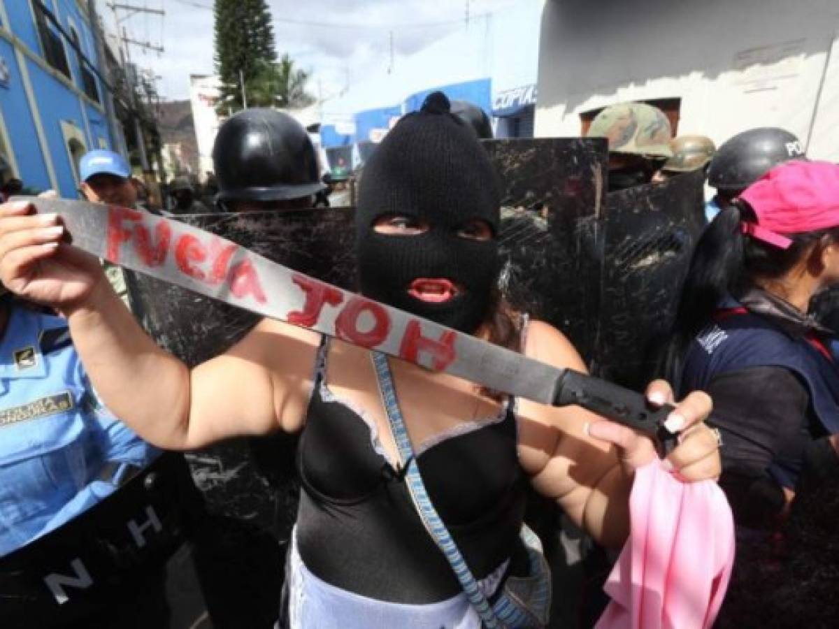 A supporter of the presidential candidate for the Honduran Opposition Alliance Against the Dictatorship in the past election, Salvador Nasralla, holds a knife reading 'JOH out', referring to reelected Hondueran President Juan Orlando Hernandez, during a protest outside the Congress building during the instalation of the first legislature of the period 2018-2022, at the National Congress in Tegucigalpa on January 25, 2018.Hernandez, who is to begin his second term on January 27 amid fraud accusations, did not attend the session. / AFP PHOTO / STR