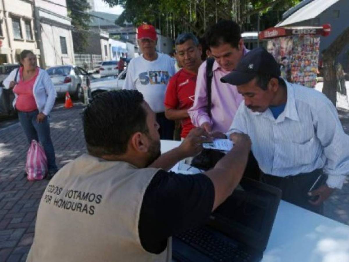 A worker of the Honduran Electoral Supreme Court (TSE) provides information helping citizens to find their polling place, ahead of Sunday's national elections, in Tegucigalpa on November 25, 2017.Honduras is going into elections on Sunday that, if voter surveys are right, will see current President Juan Orlando Hernandez given a new four-year mandate -- despite a one-term limit in the constitution. His conservative National Party contends that a 2015 Supreme Court ruling voided that restriction. But the opposition disputes that, saying the court does not have the power to overrule the constitution. / AFP PHOTO / RODRIGO ARANGUA A worker of the Honduran Electoral Supreme Court (TSE) provides information helping citizens to find their polling place, ahead of Sunday's national elections, in Tegucigalpa on November 25, 2017.Honduras is going into elections on Sunday that, if voter surveys are right, will see current President Juan Orlando Hernandez given a new four-year mandate -- despite a one-term limit in the constitution. His conservative National Party contends that a 2015 Supreme Court ruling voided that restriction. But the opposition disputes that, saying the court does not have the power to overrule the constitution. / AFP PHOTO / RODRIGO ARANGUA