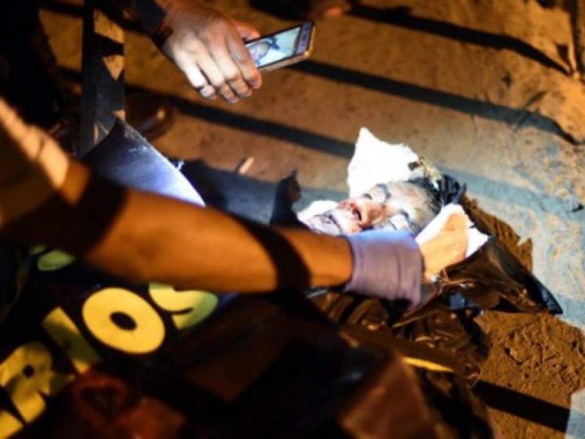A police investigator tAkes a picture of the face of a man shot dead and presenting signs of torture found at the Paraiso II neighborhood in Guatemala City on March 26, 2017. Guatemala is hit by a wave of violence that leaves about 16 murdered people every day, one of the highest rates in Latin America. / AFP PHOTO / JOHAN ORDONEZ / GRAPHIC CONTENT A police investigator tAkes a picture of the face of a man shot dead and presenting signs of torture found at the Paraiso II neighborhood in Guatemala City on March 26, 2017. Guatemala is hit by a wave of violence that leaves about 16 murdered people every day, one of the highest rates in Latin America. / AFP PHOTO / JOHAN ORDONEZ / GRAPHIC CONTENT