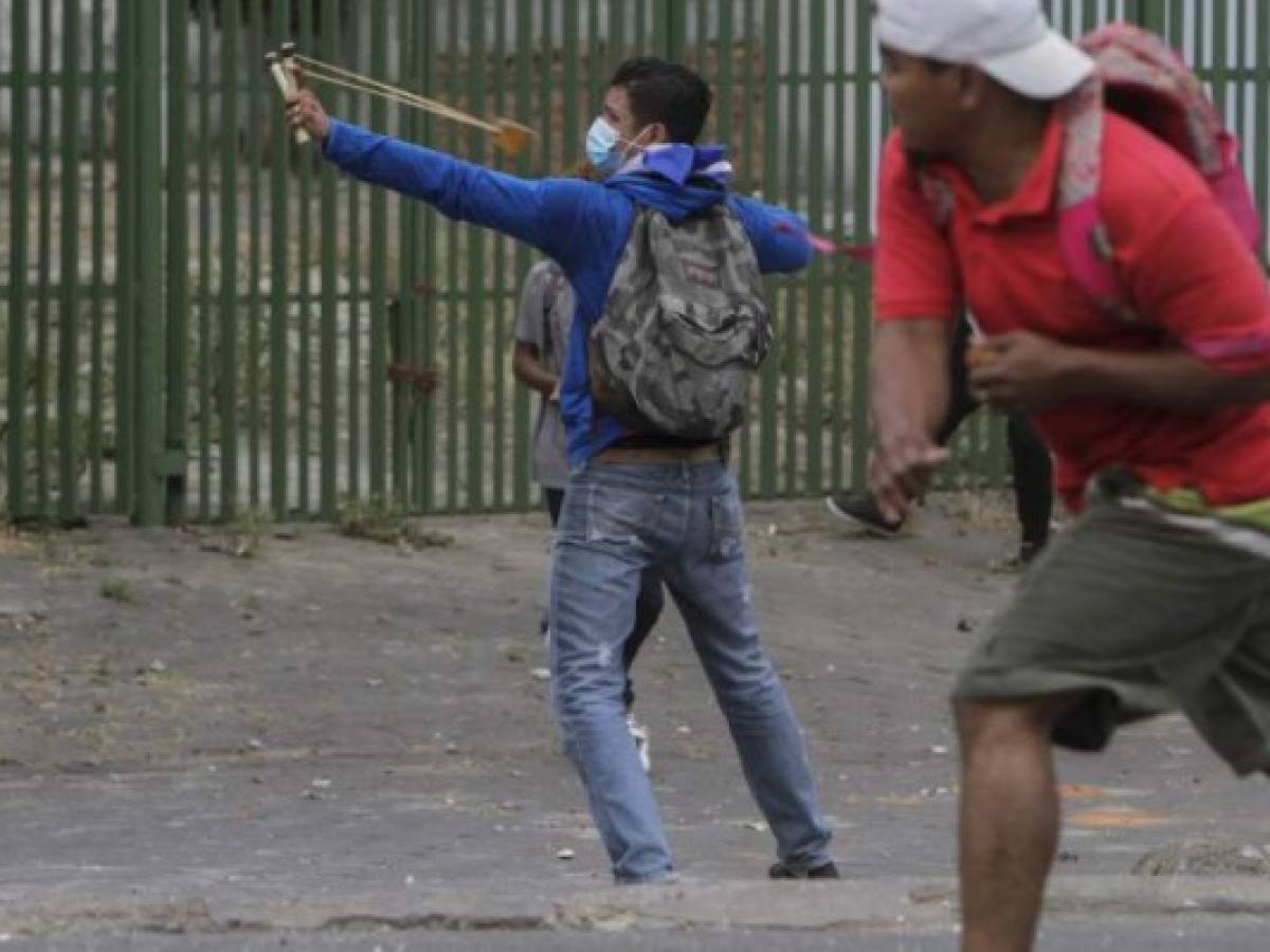 Students clash with riot police agents in front of the Engineering University during a protest against government's reforms in the Institute of Social Security (INSS) in Managua on April 20, 2018.A protester and a policeman were killed in the Nicaraguan capital Managua after demonstrations over pension reform turned violent Thursday night, officials said. The deaths came after protests by both opponents and supporters of a new law, which increases employer and employee contributions while reducing the overall amount of pensions by five percent, rocked the capital for a second day. / AFP PHOTO / INTI OCON