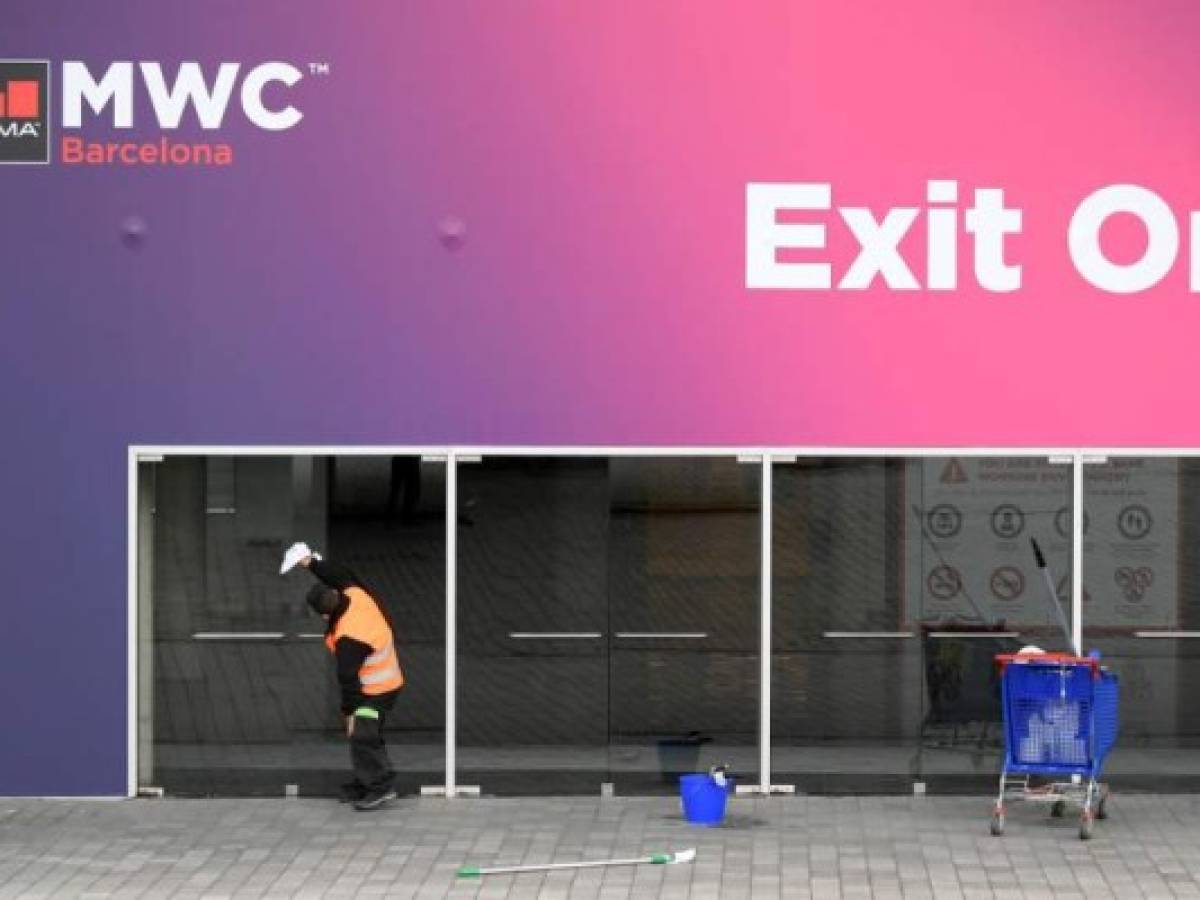 A worker cleans glass doors at the Mobile World Congress MWC venue on February 12, 2020 at the Fira Barcelona Montjuic centre in Barcelona. - Organisers of the World Mobile Congress were holding urgent talks today over the fate of the world's top mobile fair after a string of industry heavyweights withdrew over coronavirus, COVID-19, fears, a source close to the meeting said. (Photo by LLUIS GENE / AFP)