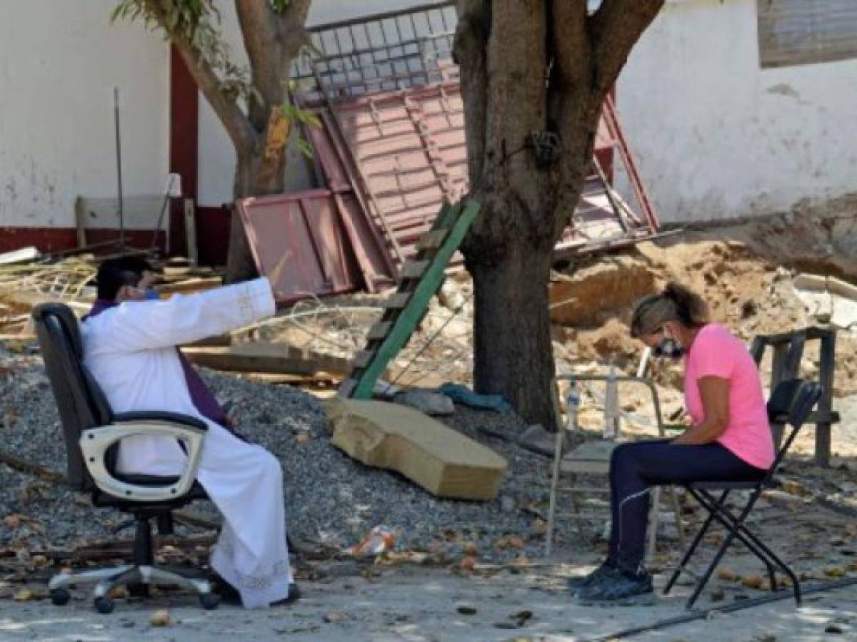 Marco Antonio Galeana, parish priest of the Cordova church, hears the confession of a devotee outside the church in Acapulco, Mexico, on April 9, 2020 during the new coronavirus COVID-19 pandemic. - Churches will be empty this Easter and Passover festivities will also take place behind closed doors owing to the COVID-19 lockdown. Christians will be obliged to turn to services broadcast on television or over social media this year owing to the coronavirus and Jews will mark the Passover holiday in their own homes rather than as communities. (Photo by Francisco Robles / AFP) Marco Antonio Galeana, parish priest of the Cordova church, hears the confession of a devotee outside the church in Acapulco, Mexico, on April 9, 2020 during the new coronavirus COVID-19 pandemic. - Churches will be empty this Easter and Passover festivities will also take place behind closed doors owing to the COVID-19 lockdown. Christians will be obliged to turn to services broadcast on television or over social media this year owing to the coronavirus and Jews will mark the Passover holiday in their own homes rather than as communities. (Photo by Francisco Robles / AFP)