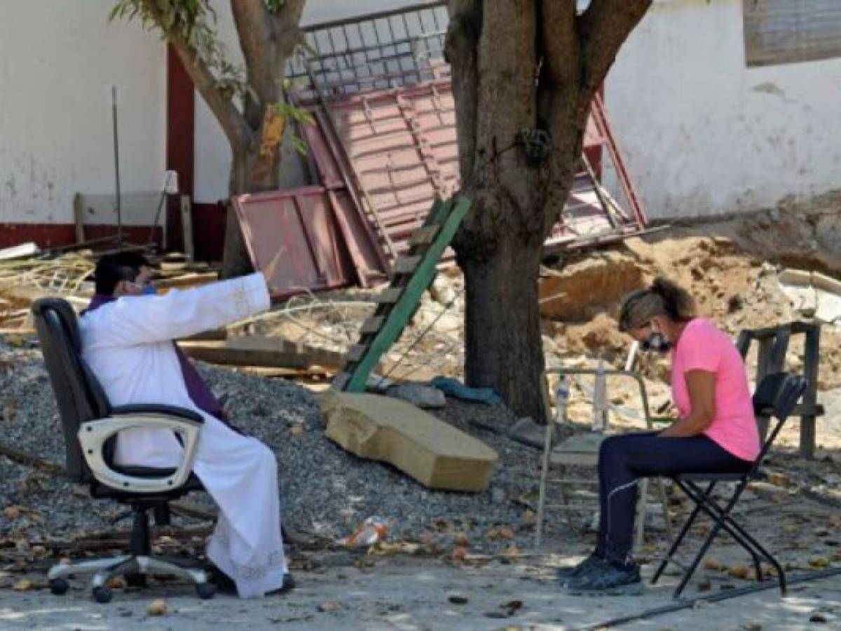 Marco Antonio Galeana, parish priest of the Cordova church, hears the confession of a devotee outside the church in Acapulco, Mexico, on April 9, 2020 during the new coronavirus COVID-19 pandemic. - Churches will be empty this Easter and Passover festivities will also take place behind closed doors owing to the COVID-19 lockdown. Christians will be obliged to turn to services broadcast on television or over social media this year owing to the coronavirus and Jews will mark the Passover holiday in their own homes rather than as communities. (Photo by Francisco Robles / AFP)