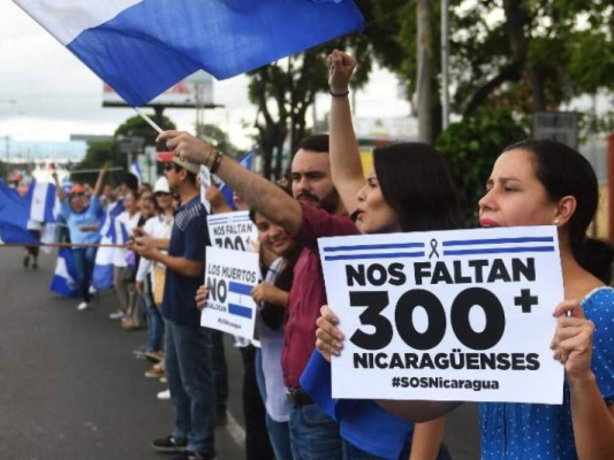 Protestas antigobierno sostienen el rótulo: 'Nos faltan 300 nicaragüenses' en la Cadena Humana que se formó entre Managua y Masaya el 4 de julio de 2018. / AFP PHOTO / MARVIN RECINOS