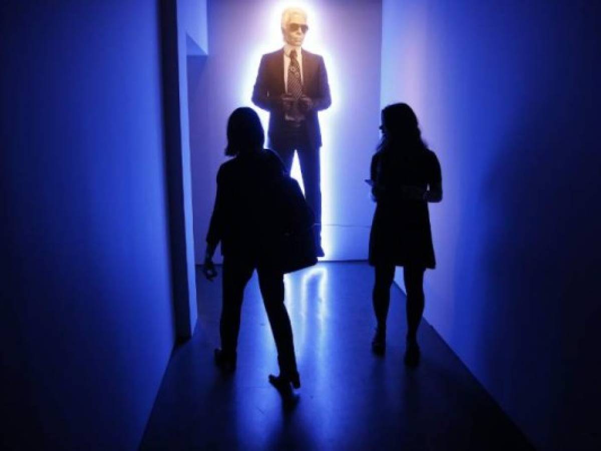 (FILES) In this file photo taken on October 15, 2015 people walk through an exhibition of German fashion designer, artist and photographer Karl Lagerfeld's photography at the Pinacotheque in Paris. - German fashion designer Karl Lagerfeld has died at the age of 85, it was announced on February 19, 2019. (Photo by FLORIAN DAVID / AFP)
