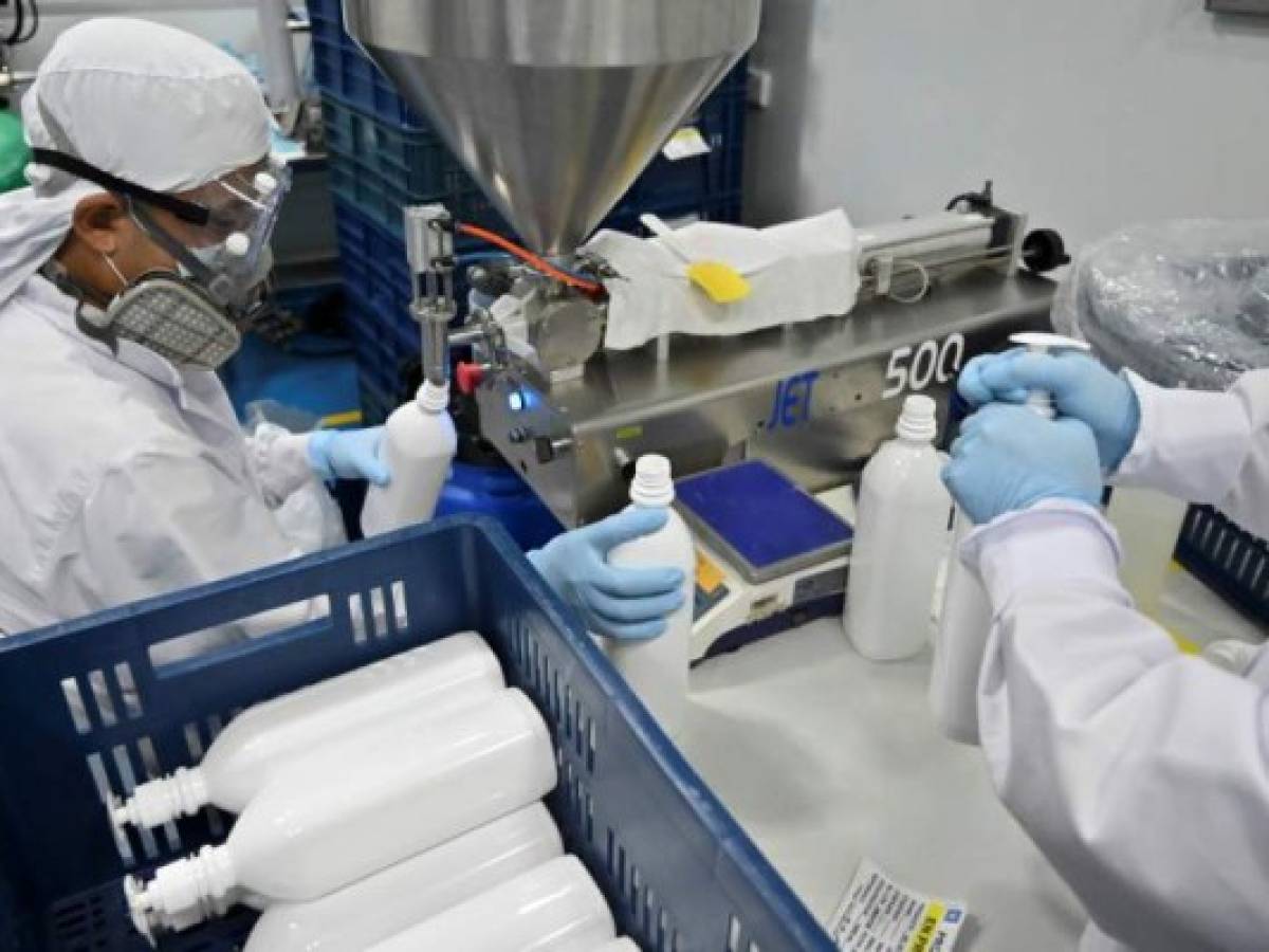 Workers prepare bottles of antibacterial gel at the cosmetics company Eurobelleza, in Cali, Colombia,on April 1, 2020 during the coronavirus COVID-19 pandemic. - Eurobelleza switched to the production of antibacterial gel and soaps to supply the high demand of hospitals and the general public and as a business alternative during the COVID-19 pandemic. (Photo by Luis ROBAYO / AFP)