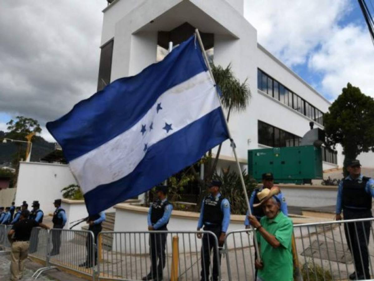 An opposition supporter waves a Honduran national flag outside the headquarters of the Mission to Support the Fight against Corruption and Impunity in Honduras (MACCIH), during a protest against the mission's cease of operations in Tegucigalpa, on January 19, 2020. - An anti-corruption commission set up in Honduras four years ago will cease operations on Sunday, the Organization of American States said after failing to reach a deal on extending operations in the graft-riddled country. (Photo by ORLANDO SIERRA / AFP)