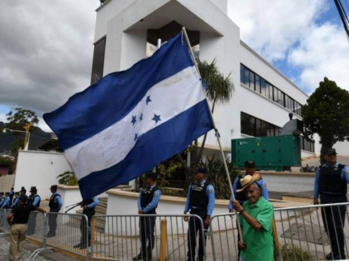 An opposition supporter waves a Honduran national flag outside the headquarters of the Mission to Support the Fight against Corruption and Impunity in Honduras (MACCIH), during a protest against the mission's cease of operations in Tegucigalpa, on January 19, 2020. - An anti-corruption commission set up in Honduras four years ago will cease operations on Sunday, the Organization of American States said after failing to reach a deal on extending operations in the graft-riddled country. (Photo by ORLANDO SIERRA / AFP) An opposition supporter waves a Honduran national flag outside the headquarters of the Mission to Support the Fight against Corruption and Impunity in Honduras (MACCIH), during a protest against the mission's cease of operations in Tegucigalpa, on January 19, 2020. - An anti-corruption commission set up in Honduras four years ago will cease operations on Sunday, the Organization of American States said after failing to reach a deal on extending operations in the graft-riddled country. (Photo by ORLANDO SIERRA / AFP)