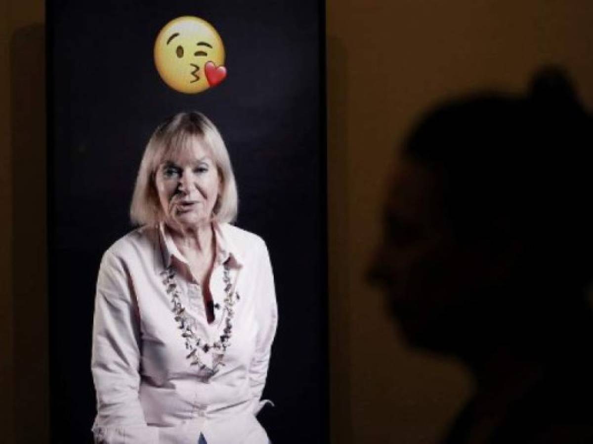 A visitor whose shadow is seen on the wall (R), watches a video installation of a woman using emojis to talk, at the exhibition 'Emoglyphs: Picture-Writing from Hieroglyphs to the Emoji' at the Israel Museum in Jerusalem, on December 19, 2019. - The exhibition, open until late 2020, aims to convey the importance of ancient hieroglyphics to modern audiences glued to their phones through the cunning use of emojis, by comparing the pictograms of antiquity to those of today. (Photo by MENAHEM KAHANA / AFP)