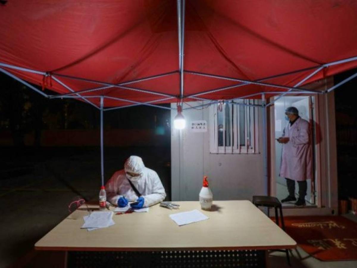 This photo taken on February 3, 2020 shows medical staff members working at a quarantine zone in Wuhan, the epicentre of the new coronavirus outbreak, in China's central Hubei province. - The number of total infections in China's coronavirus outbreak has passed 20,400 nationwide with 3,235 new cases confirmed, the National Health Commission said on February 4. (Photo by STR / AFP) / China OUT