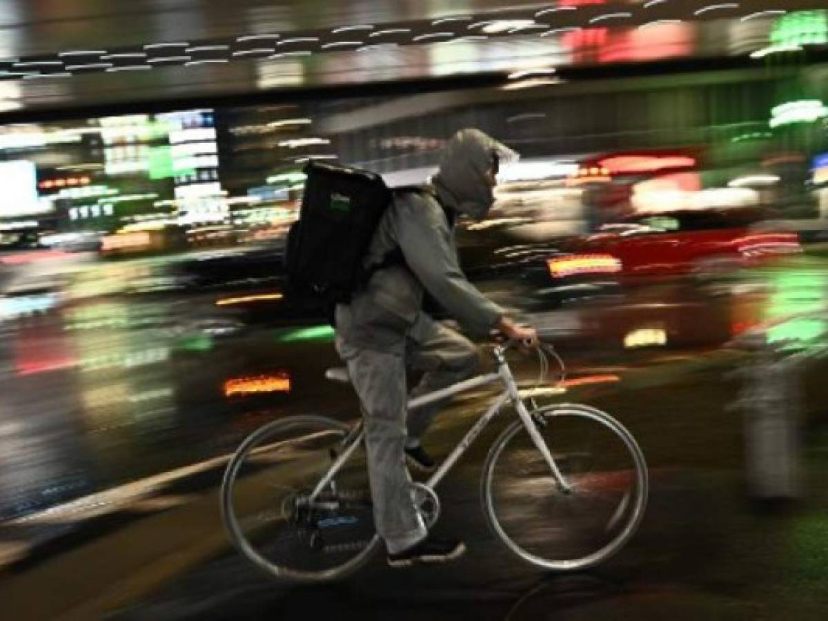 An employee of a food delivery company rides a bike in Roppongi district of Tokyo on April 9, 2020. (Photo by Philip FONG / AFP)