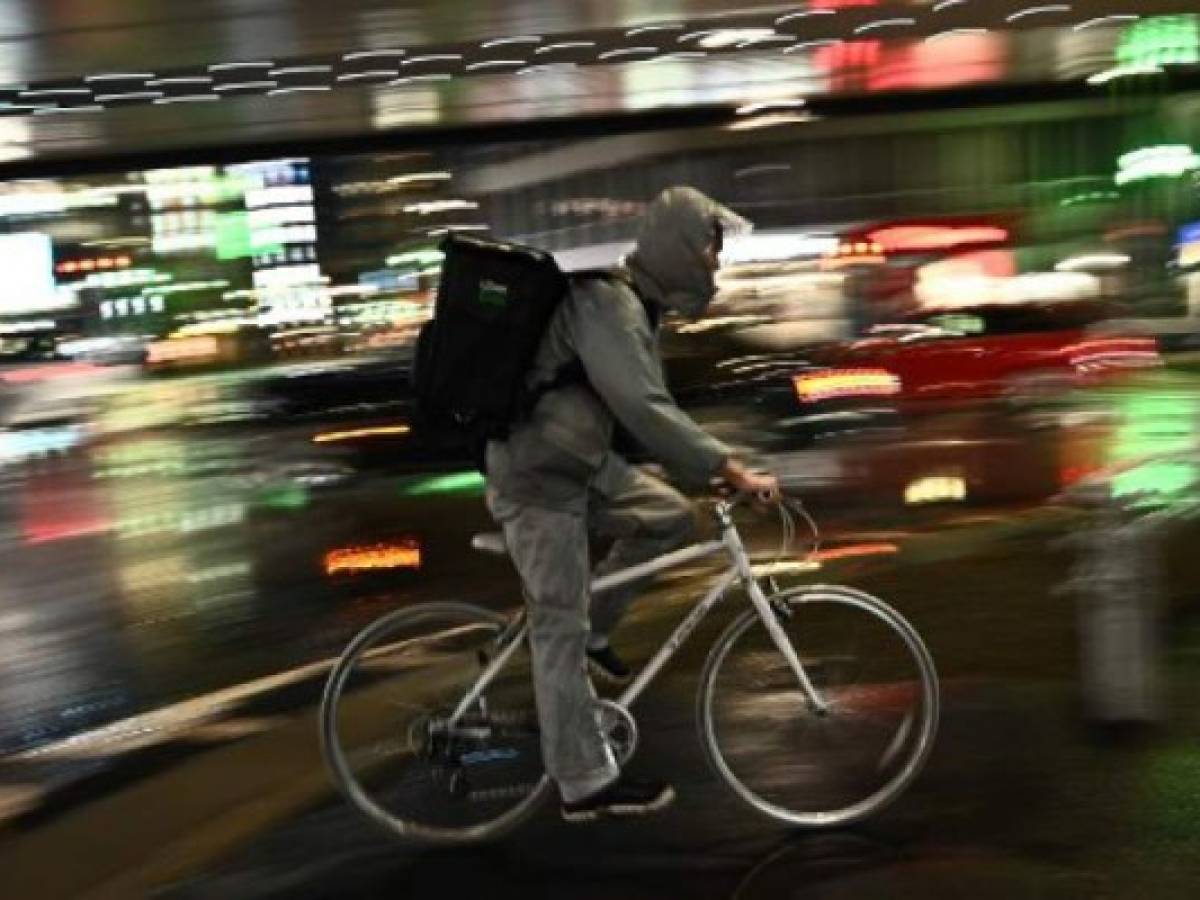 An employee of a food delivery company rides a bike in Roppongi district of Tokyo on April 9, 2020. (Photo by Philip FONG / AFP) An employee of a food delivery company rides a bike in Roppongi district of Tokyo on April 9, 2020. (Photo by Philip FONG / AFP)