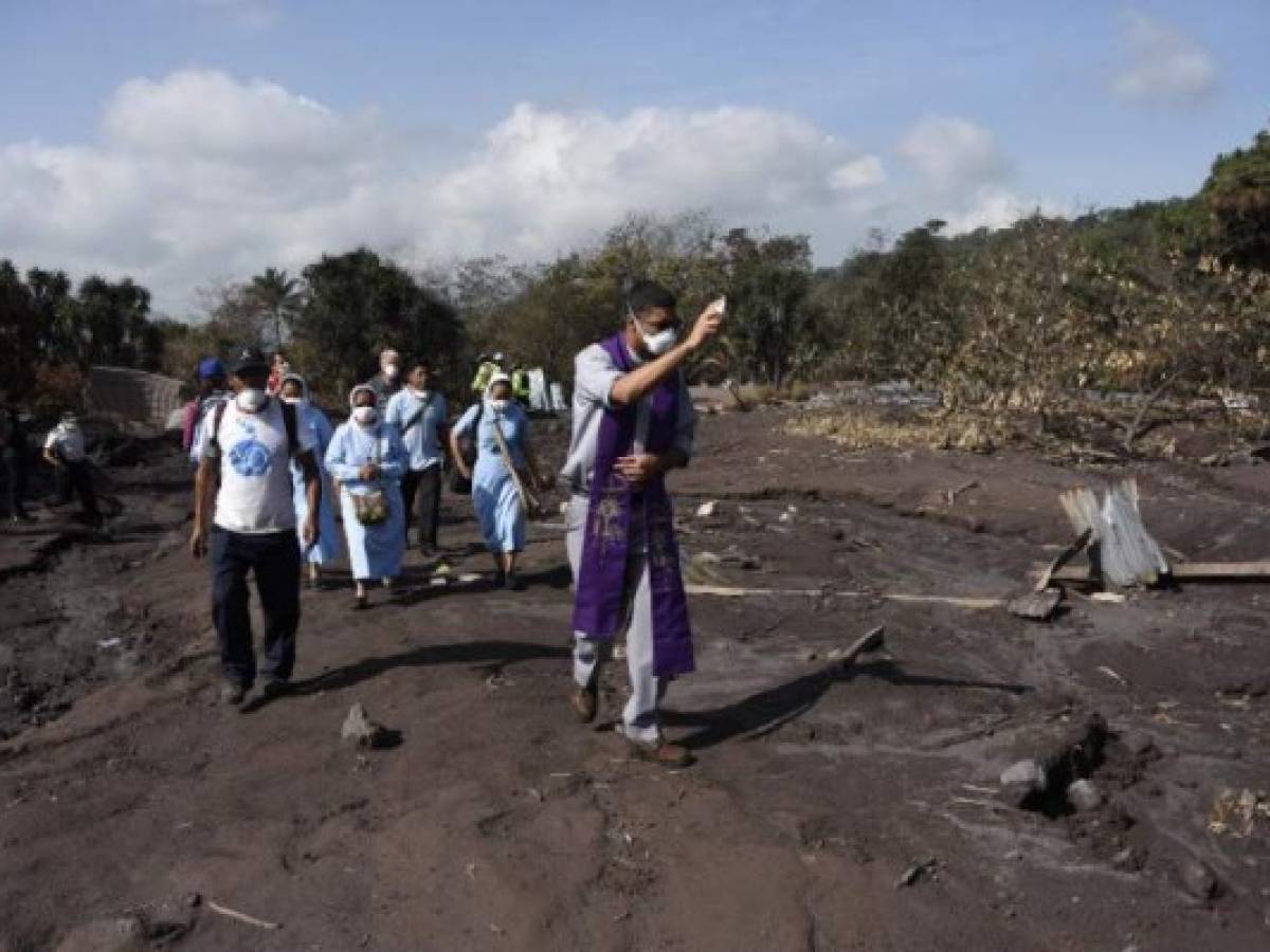 El padre Eliecer Rodríguez bendice la zona de desastre donde aún se buscan víctimas de la erupción del volcán de Fuego, en San Miguel Los Lotes, en Escuintla / AFP PHOTO / Johan ORDONEZ