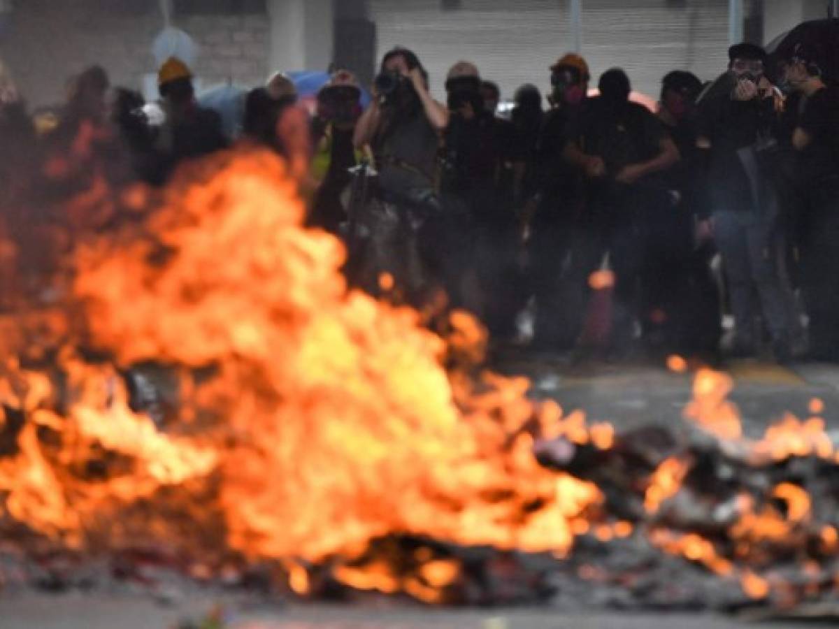 Protesters look on as a barricade burns during rallies and protests through the streets of Hong Kong on October 1, 2019, as the city observes the National Day holiday to mark the 70th anniversary of communist China's founding. - Police fanned out across Hong Kong on October 1 in a bid to deter pro-democracy protests as the city marked communist China's 70th birthday, with local officials attending a closed door flag-raising ceremony behind closed doors. (Photo by Anthony WALLACE / AFP)