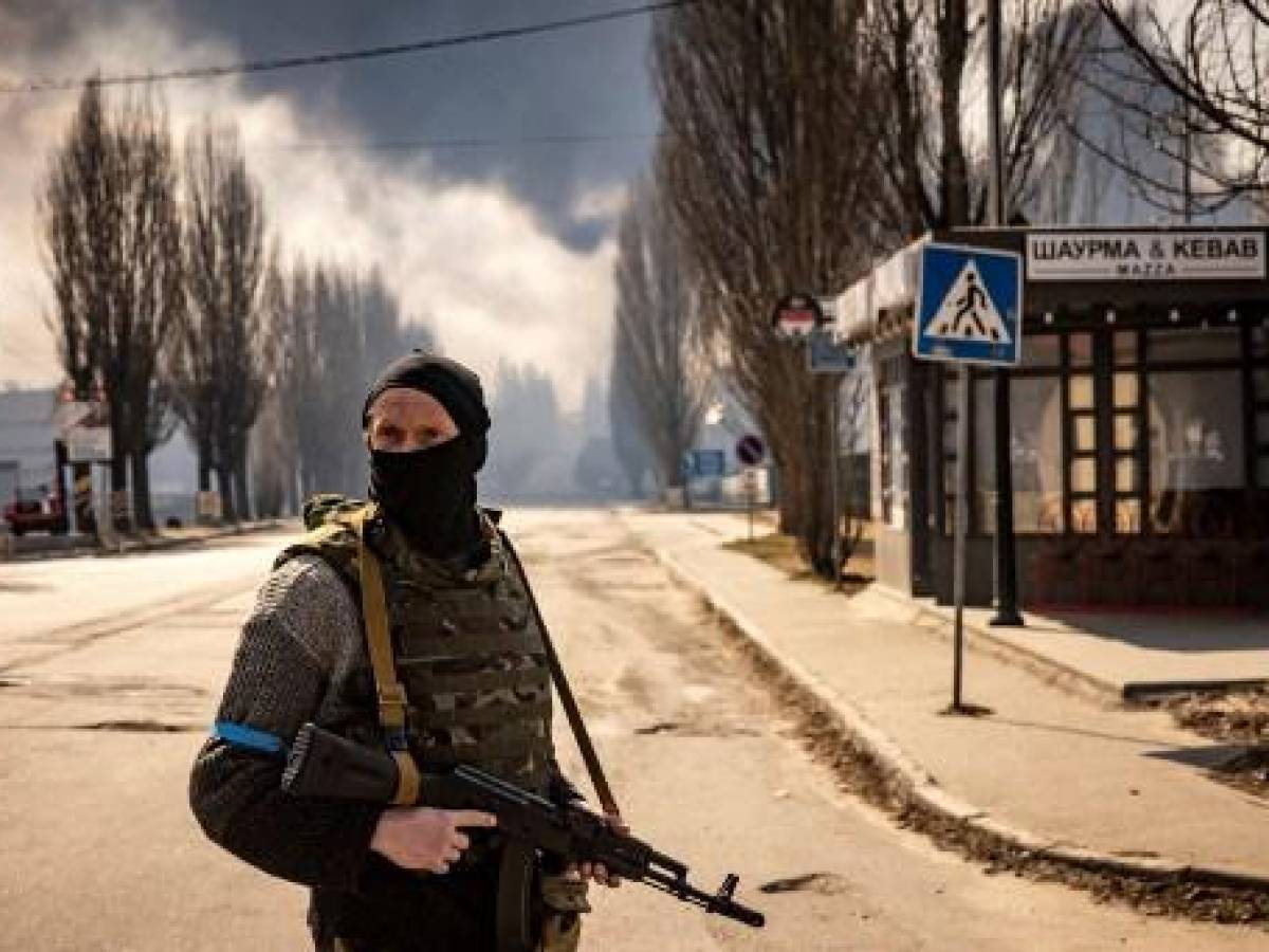 Un soldado ucraniano aguarda cerca de una bodega en llamas tras ataques de Rusia en Kiev, el 24 de marzo de 2022. (Photo by FADEL SENNA / AFP)