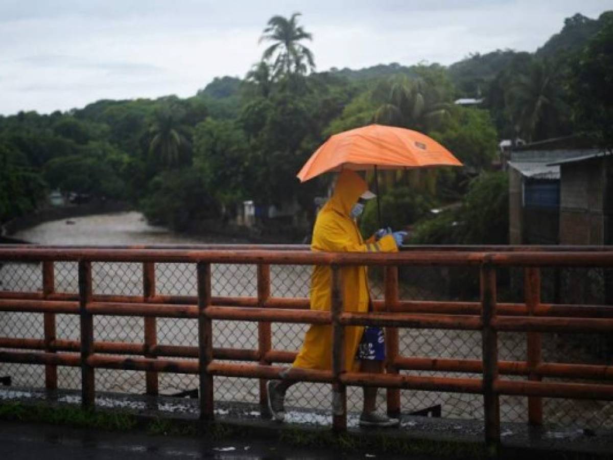 A man crosses a bridge over the Chilama River in La Libertad one of the areas hardest hit by Tropical Storm Amanda in El Salvador, on June 1, 2020. - Storm Amanda left a trail of destruction and death as it passed through northern Central America, where 18 people died and countless houses and roads were devastated by the cyclone, especially in El Salvador, the country worst beaten. (Photo by Marvin RECINOS / AFP) A man crosses a bridge over the Chilama River in La Libertad one of the areas hardest hit by Tropical Storm Amanda in El Salvador, on June 1, 2020. - Storm Amanda left a trail of destruction and death as it passed through northern Central America, where 18 people died and countless houses and roads were devastated by the cyclone, especially in El Salvador, the country worst beaten. (Photo by Marvin RECINOS / AFP)