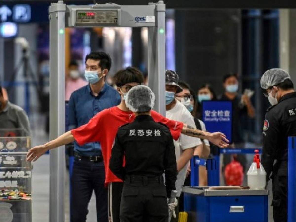 Passengers wearing facemasks go through a check-point following preventive procedures against the spread of the COVID-19 coronavirus at one of the entries to the Pudong International Airport in Shanghai on June 11, 2020. (Photo by Hector RETAMAL / AFP) Passengers wearing facemasks go through a check-point following preventive procedures against the spread of the COVID-19 coronavirus at one of the entries to the Pudong International Airport in Shanghai on June 11, 2020. (Photo by Hector RETAMAL / AFP)