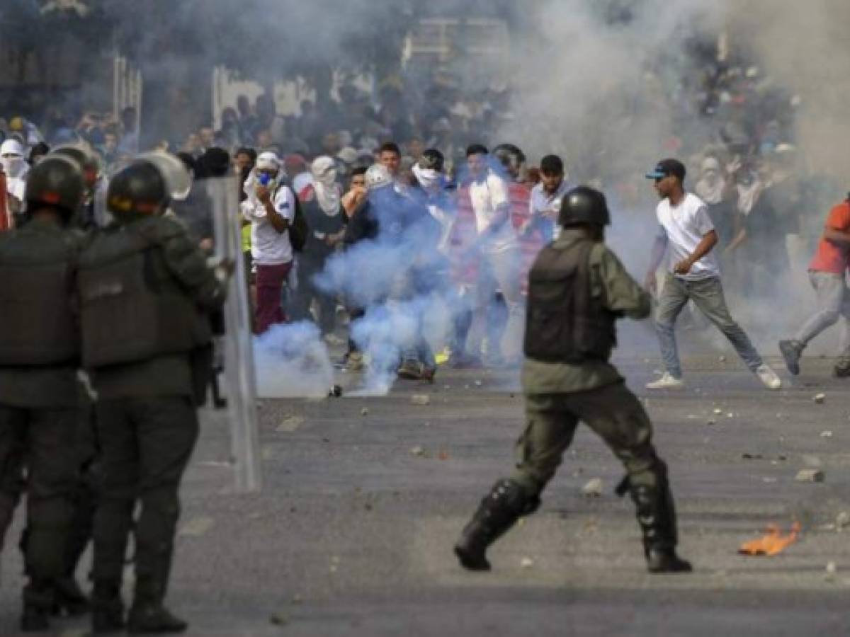 Opposition demonstrators clash with security forces during a protest against the government of President Nicolas Maduro on the anniversary of the 1958 uprising that overthrew the military dictatorship, in Caracas on January 23, 2019. - Venezuela's National Assembly head Juan Guaido declared himself the country's 'acting president' on Wednesday during a mass opposition rally against leader Nicolas Maduro. (Photo by Yuri CORTEZ / AFP)