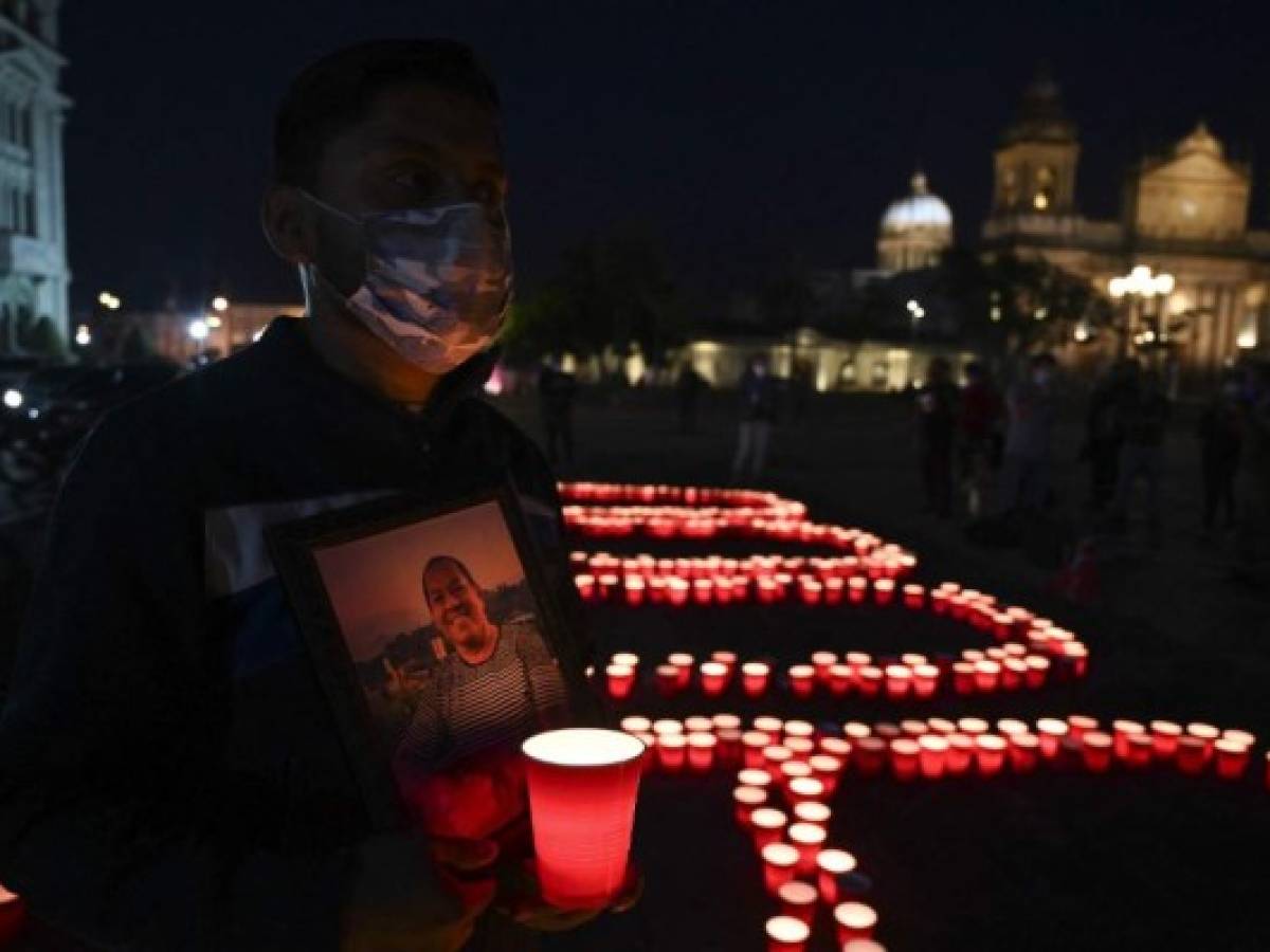 Alex García sostiene un retrato de su padre René García, de 59 años, víctima del COVID-19, durante un homenaje en homenaje a las más de 9000 personas que murieron por la enfermedad en el país, en la Ciudad de Guatemala, el 26 de junio de 2021. (Foto por Johan ORDONEZ / AFP)