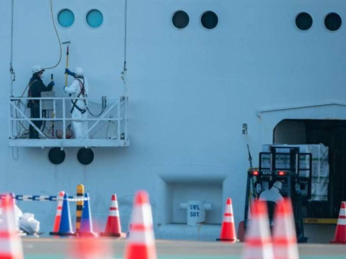 Crew members in protective clothing clean the the Diamond Princess cruise ship at Daikoku pier cruise terminal in Yokohama on February 24, 2020. - Despite a quarantine imposed on the Diamond Princess, more than 600 people on board tested positive for the coronavirus, with several dozen in serious condition. (Photo by Philip FONG / AFP)