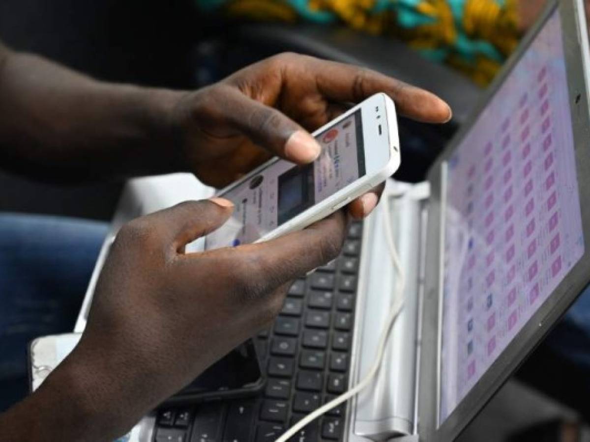 A student of the Virtual University of Ivory Coast (UVCI) takes a class on his mobile phone on November 28, 2019 in Abidjan - The first promotion of the Virtual University of Ivory Coast (UVCI), or 830 students, graduated on November 28, receiving a degree in the digital sciences, issued by this institution created in 2015 to unclog the university system. (Photo by ISSOUF SANOGO / AFP)