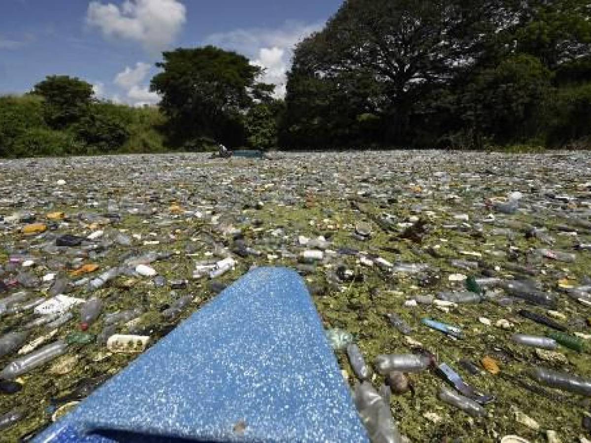 Residuos de plástico, vidrio y otros materiales son vistos en el embalse Cerron Grande en Potonico, El Salvador, el 9 de septiembre de 2022. - Arrastrados por diferentes afluentes, inmensos depósitos de plástico multicolor cubren como un manto las tranquilas aguas del lago de Suchitlán en El Salvador. Lo mismo sucede en las paradisíacas playas del Caribe hondureño, que reciben miles de toneladas de desechos de Guatemala. (Foto por MARVIN RECINOS / AFP)