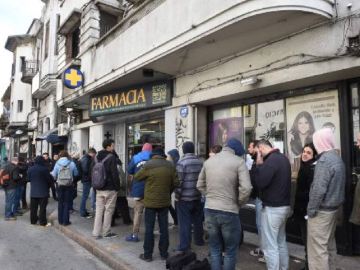 En una farmacia de la Ciudad Vieja de Montevideo, en el centro de la ciudad, compradores hacían fila para adquirir la droga, por primera vez de forma legal. La fila se extendía a la acera. En una farmacia de la Ciudad Vieja de Montevideo, en el centro de la ciudad, compradores hacían fila para adquirir la droga, por primera vez de forma legal. La fila se extendía a la acera.