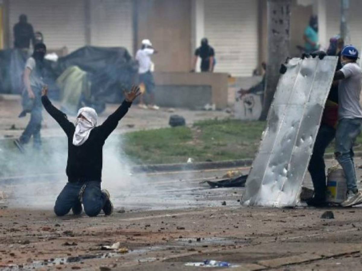 Demonstrators clash with riot police during a protest against a tax reform bill launched by President Ivan Duque, despite the president then ordered the proposal be withdrawn from Congress, in Cali, Colombia, on May 3, 2021. - Protesters in Colombia on Monday called for a new mass rally after 19 people died and more than 800 were wounded in clashes during five days of demonstrations against a proposed government tax reform. (Photo by Luis ROBAYO / AFP)