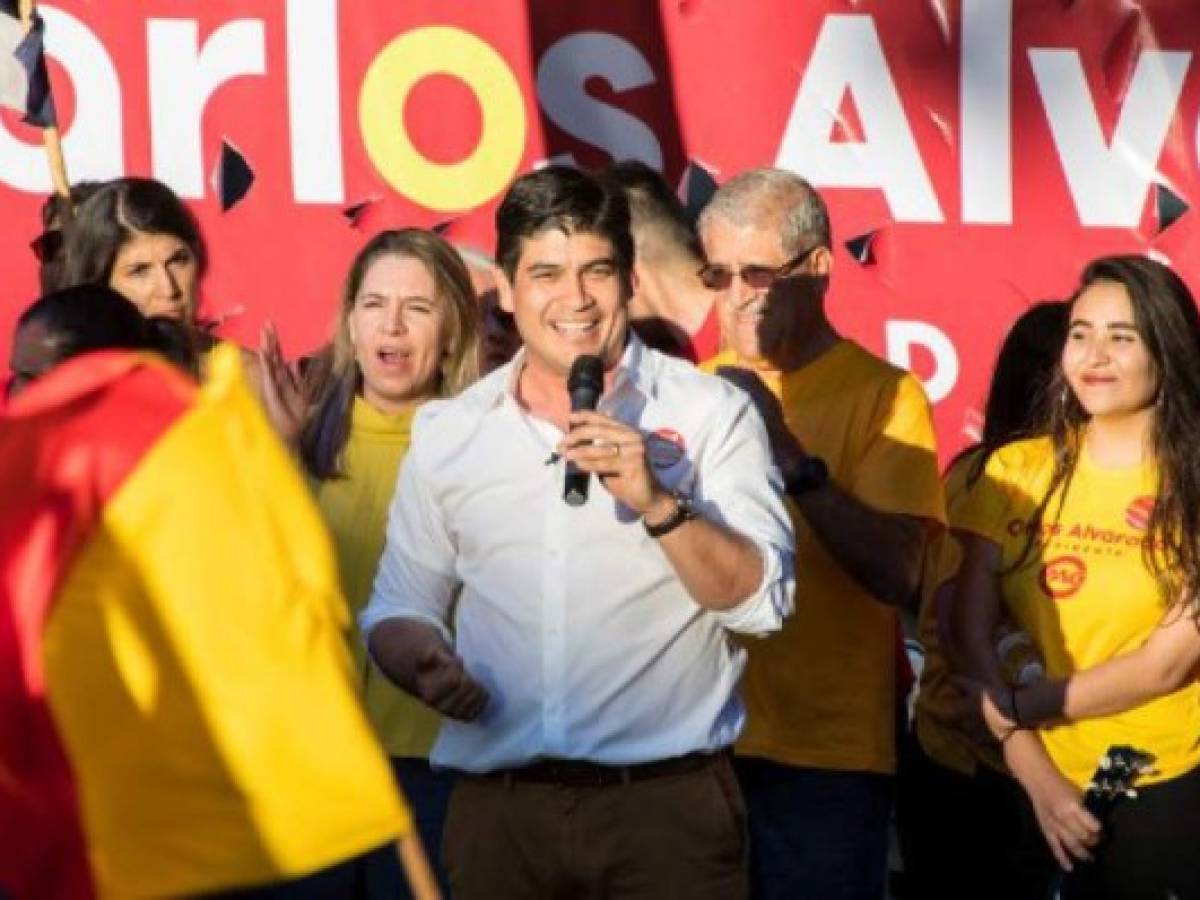 The presidential candidate of the Citizen Action Party (PAC), Carlos Alvarado (C), and his wife Caludia Dobles (C-L) take part in the election campaign closing rally with supporters in San Jose, Costa Rica, on January 28, 2018. / AFP PHOTO / Ezequiel BECERRA