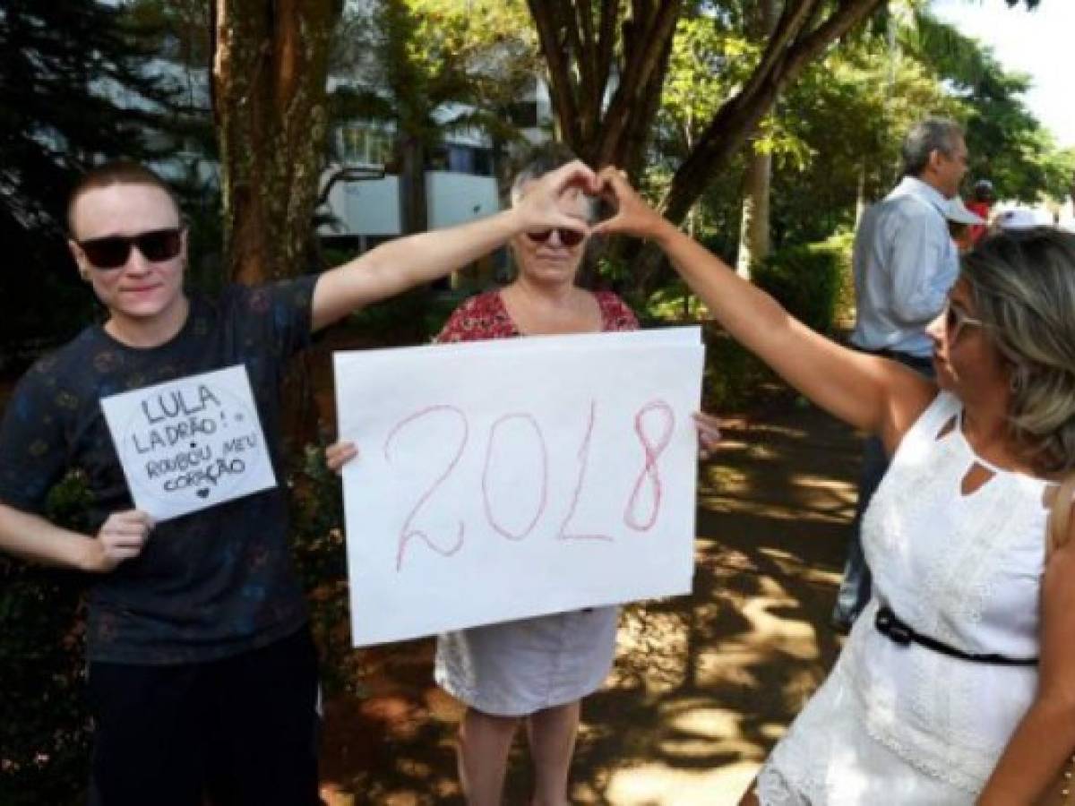 Supporters of former Brazilian President Luiz Inacio Lula da Silva demonstrate outside the federal court building in Brasilia while Lula testifies, on March 14, 2017.Lula is accused of attempting to prevent Nestor Cervero, a former head of oil giant Petrobras, from testifying in a plea bargain deal in the Lava Jato anti-corruption operation investigating the bribes scandal involving the state-run company. / AFP PHOTO / EVARISTO SA