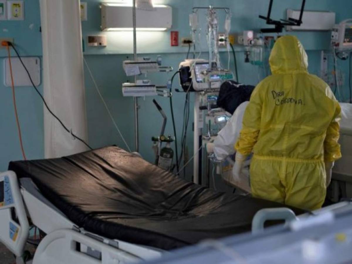 An intensivist nurse and doctor check the artificial respiration devices and medications applied to a patient infected with COVID-19, next to an empty bed where hours before a patient died of the novel coronavirus, in the intensive care unit of the San Rafael Hospital in Santa Tecla, La Libertad, just 10 km from the Salvadorean capital San Salvador, on May 16, 2020. - The San Rafael Hospital, which has been assigned to care for 100 COVID-19 patients whose cases range from 'severe to critical,' is leading in their recovery, and part of the success, according to hospital director Yeerles Luis Ramirez, has been early treatment. (Photo by Yuri CORTEZ / AFP)