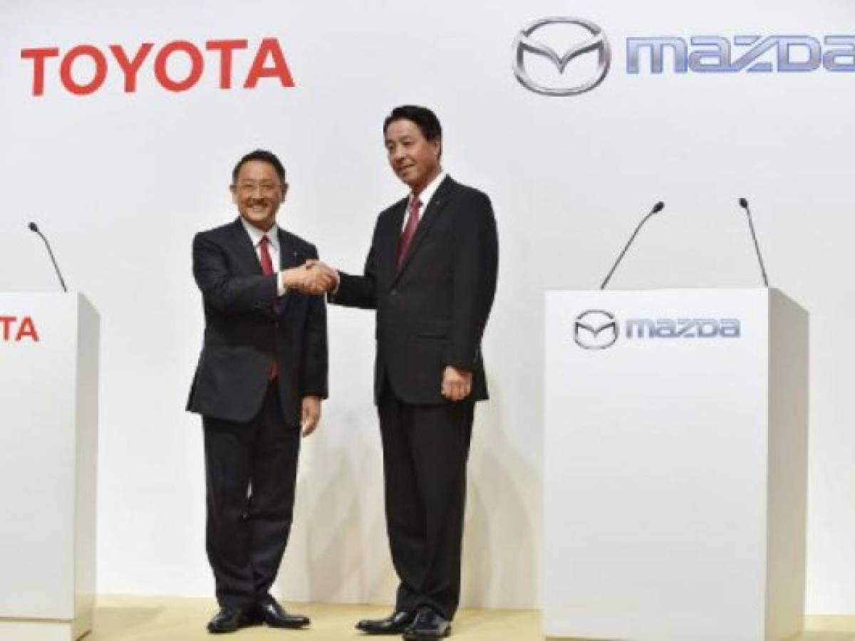 Toyota Motor Corporation President Akio Toyoda (L) shakes hands with Mazda Motor Corporation President and CEO Masamichi Kogai (R) prior to their joint press conference at a hotel in Tokyo on August 4, 2017. Japanese auto giant Toyota and smaller rival Mazda said on August 4 they agreed a capital tie-up to focus on joint development of electric vehicles, while building a 1.6 billion USD factory in the United States which will create up to 4,000 jobs. / AFP PHOTO / Kazuhiro NOGI